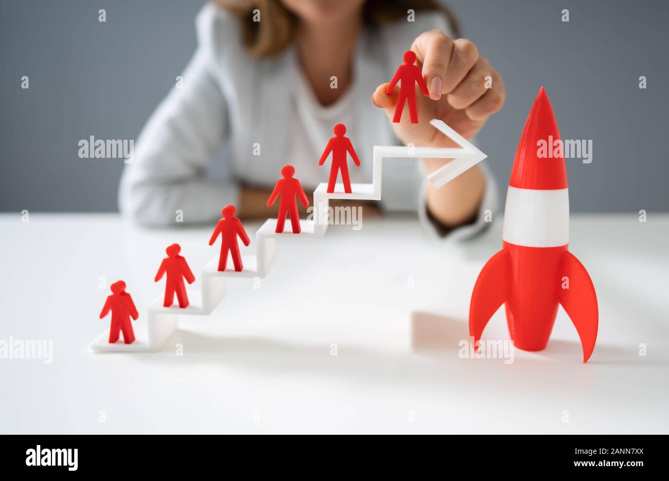 Mujer colocando rojo sobre blanco permanente de figurillas humanas crecientes gráfico de flecha cerca de la Red Rocket Foto de stock