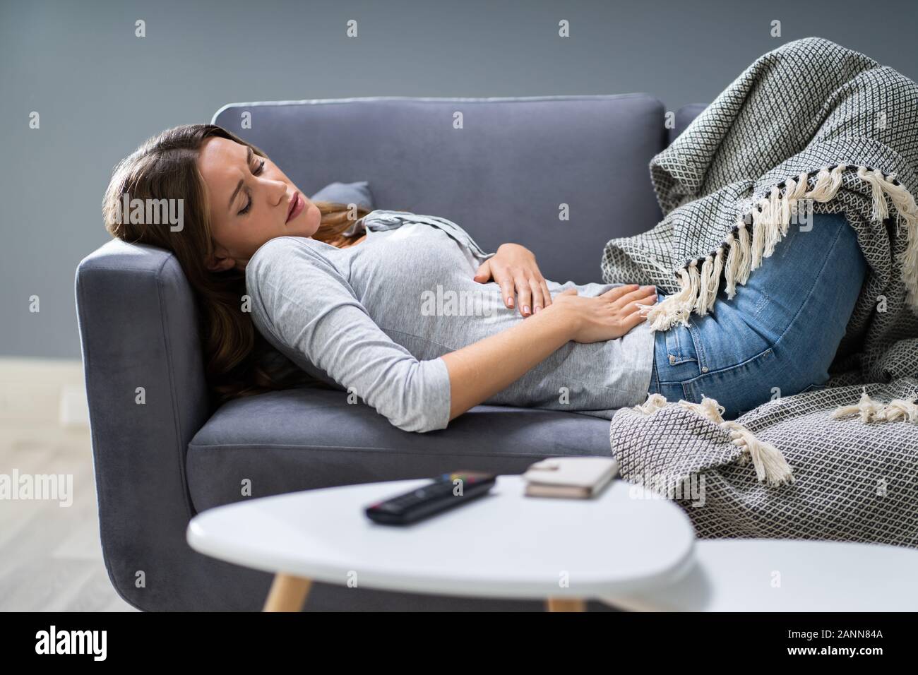 Un alto ángulo de vista de joven mujer sufre de dolor de estómago en el sofá en casa Foto de stock