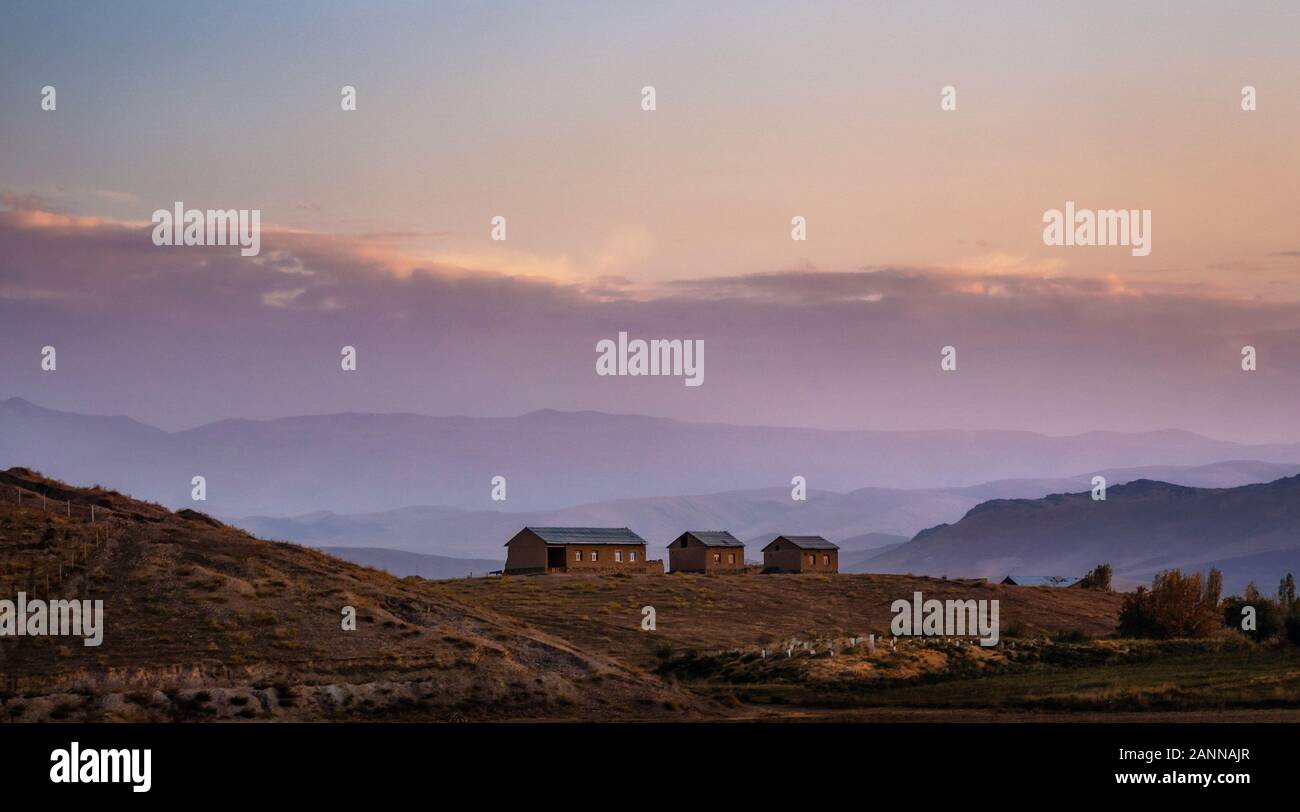 Valle de montaña con casas en la cima de la colina al atardecer en Uzbekistán Foto de stock