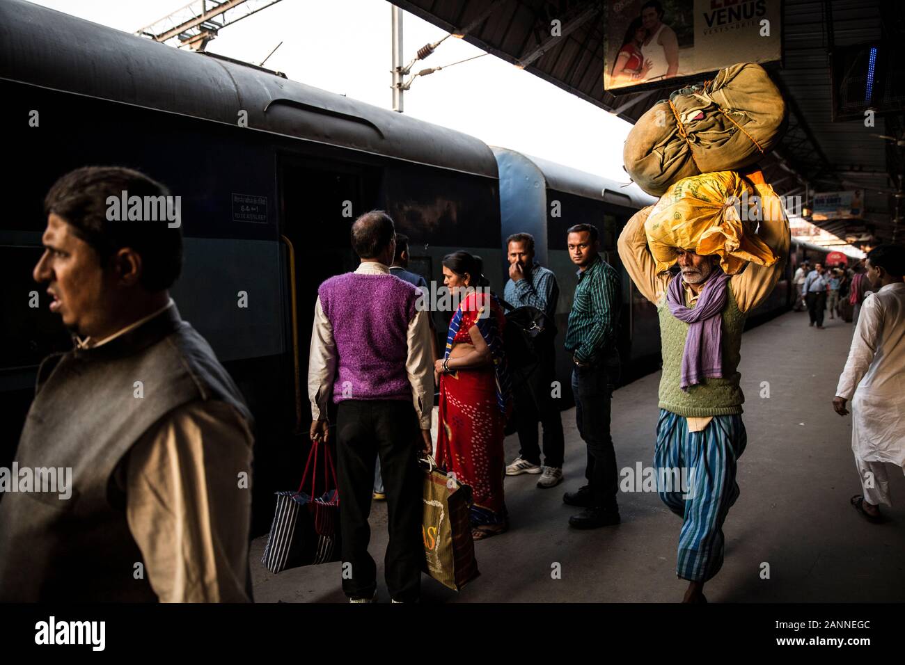 Hombre cargando bolsas sobre su cabeza en Varanasi y estación de tren. Varanasi, India Foto de stock