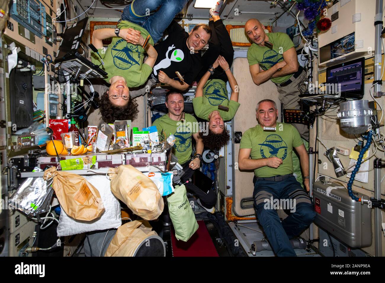 ISS - 31 Dic 2019 - La expedición de seis miembros de la tripulación es 61 reunidos en el interior del módulo de Servicio Zvezda para una cena de Nochevieja. El sentido de las agujas del reloj desde Foto de stock