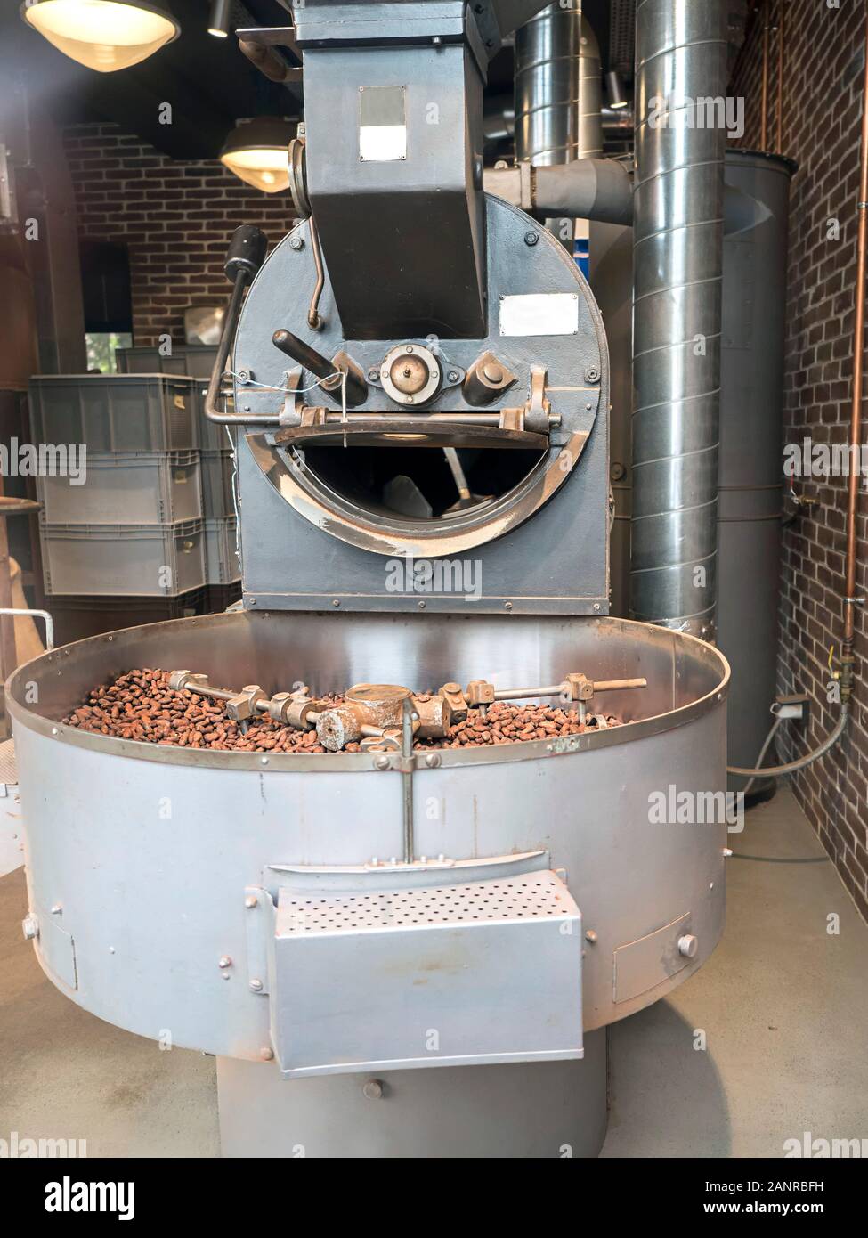 Un bean tostadora con una bandeja llena de granos de cacao se encuentra  dentro de un edificio industrial Fotografía de stock - Alamy