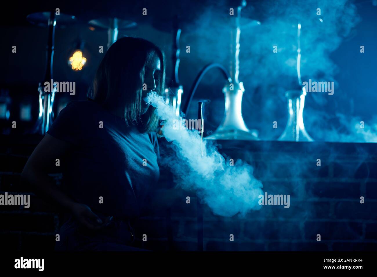 Bella mujer en night club fumar hookah o shisha bar, fondo azul Fotografía  de stock - Alamy