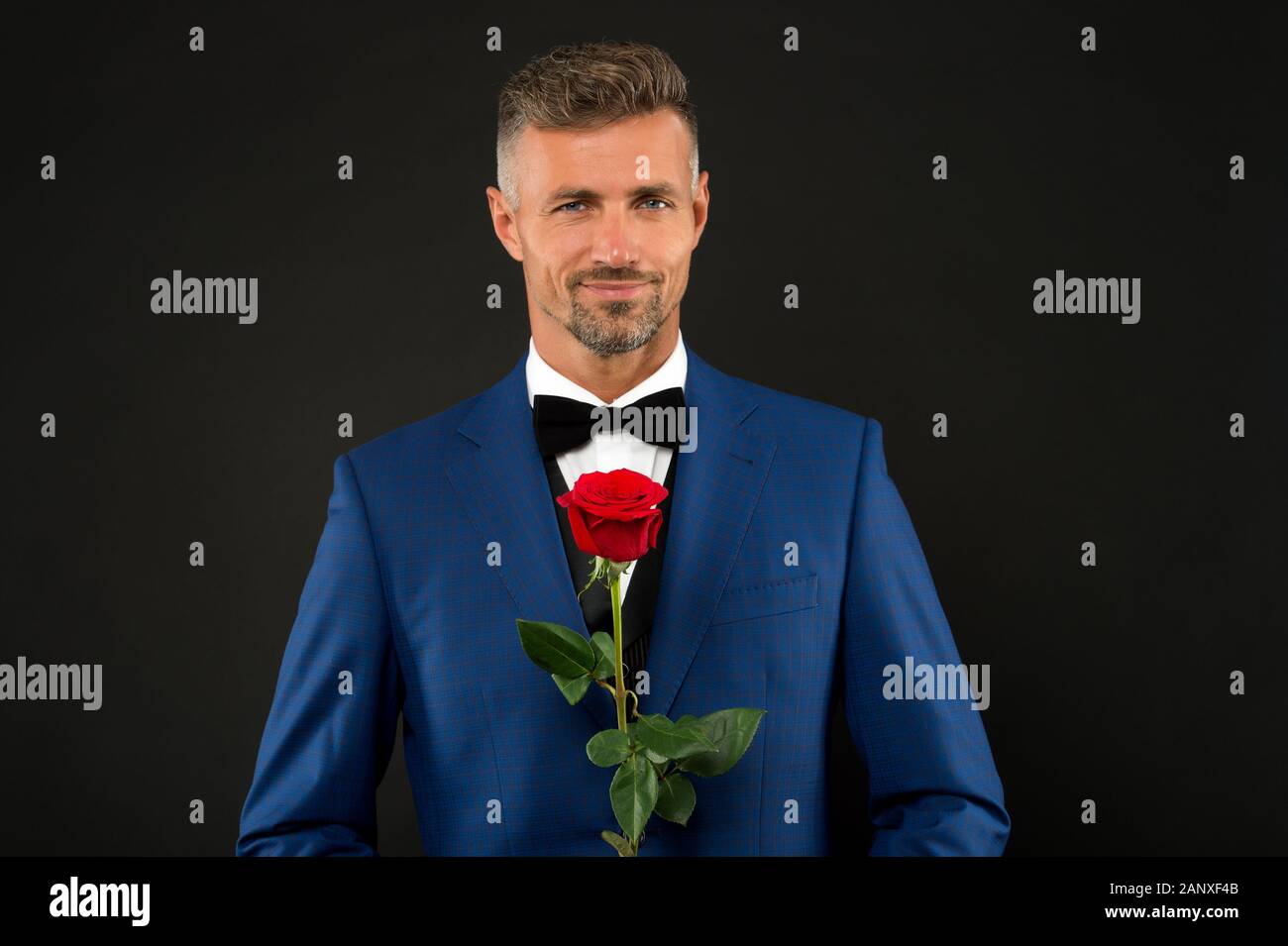 Adorable rostro de hombres. El novio de smoking con rosa. Durante