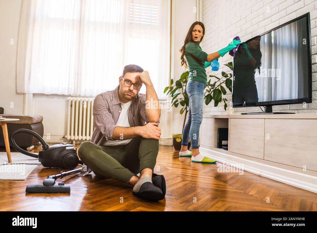 El hombre es perezoso. Su esposa está diciéndole a continuar la limpieza de su apartamento. Foto de stock