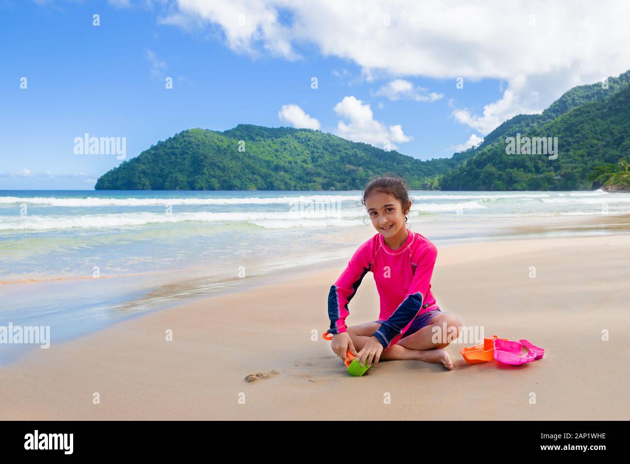 Niña jugando con arena en las Maracas Bay Beach Trinidad y Tobago sentados al aire libre actividad divertida sonriente Foto de stock