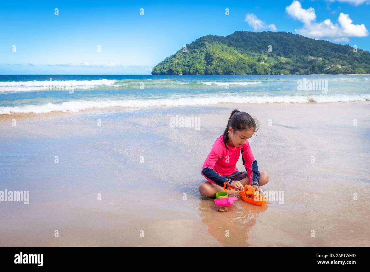 Niña jugando con arena en las Maracas Bay Beach Trinidad y Tobago sentados al aire libre actividad divertida Foto de stock