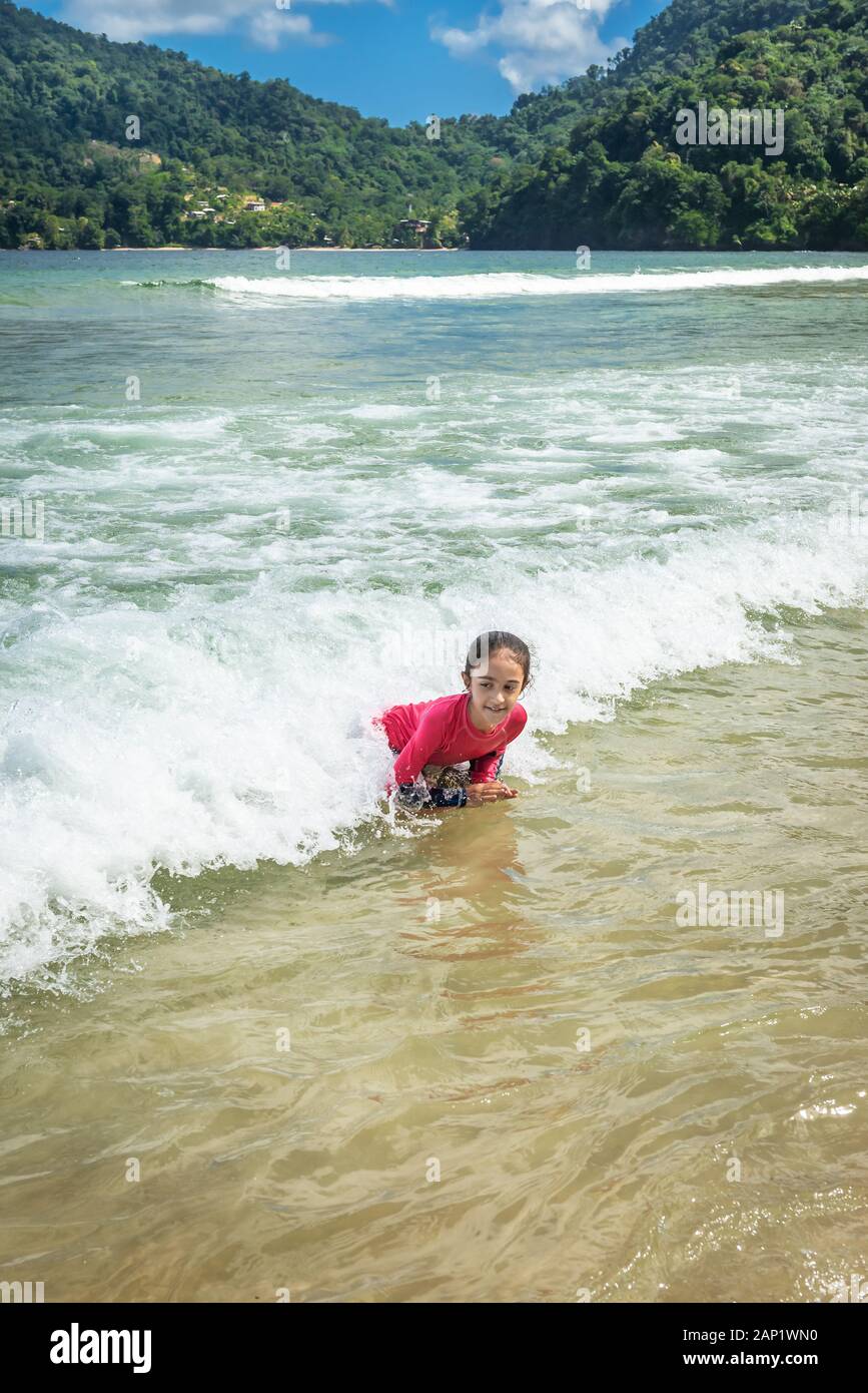 Niña nadando en las Maracas Bay Beach Trinidad y Tobago divertirse chapoteando en las olas Foto de stock