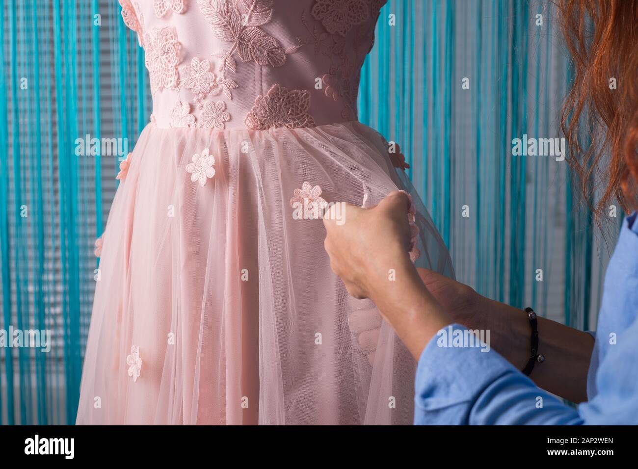 El proceso de confección de ropa. Diseñador profesional, handmade artesano,  cose flores en un vestido rosado, sobre un maniquí, en un taller. La  sastrería, wome Fotografía de stock - Alamy