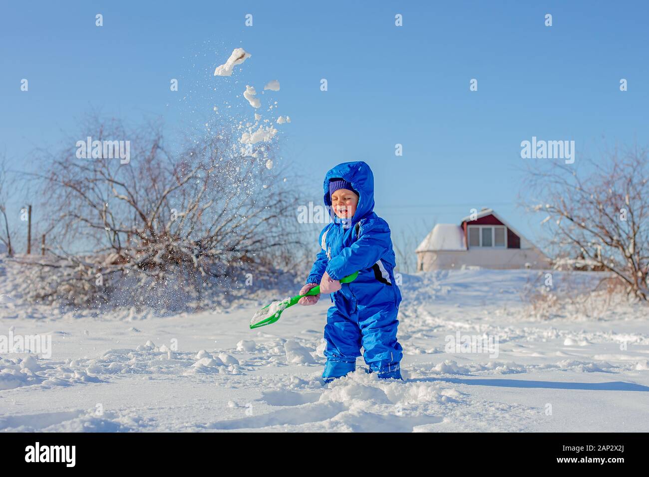 Niñito dig y jugar en el invierno, nieve, actividades de invierno para niños. Niño excava una pala de nieve. Niño con sus manos en posee una espada roja. Holi de