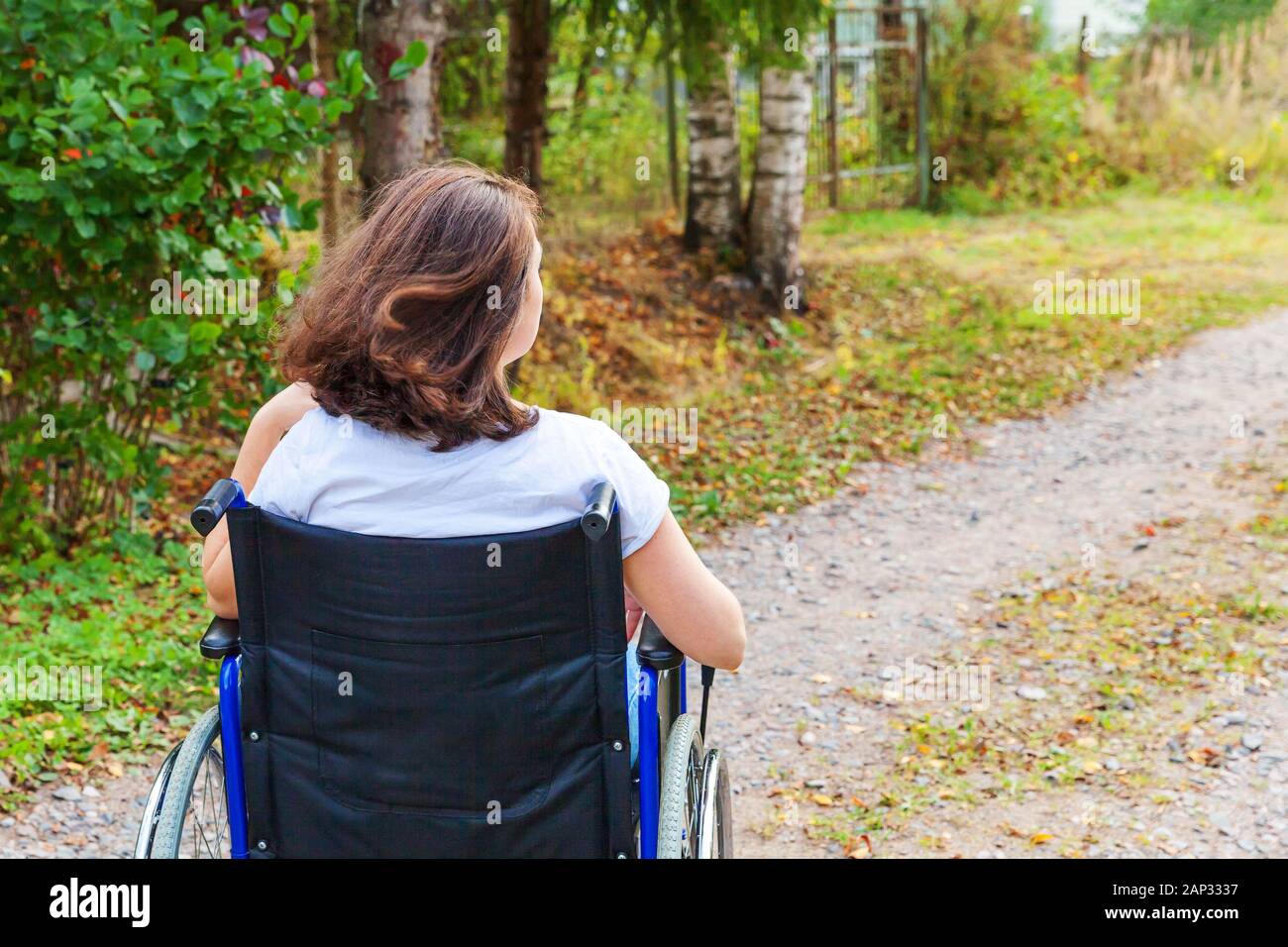 Mujer joven feliz handicap en silla de ruedas en la carretera en el hospital Park disfruta de libertad. Niña paralizada en silla no válida para personas discapacitadas en la naturaleza al aire libre. Concepto de rehabilitación Foto de stock