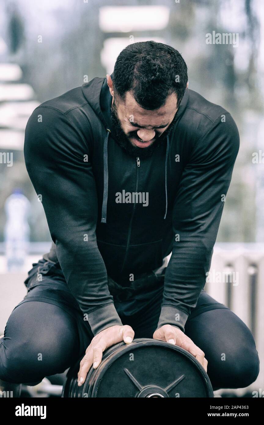 Joven en ropa deportiva y auriculares trabaja con pesas en el