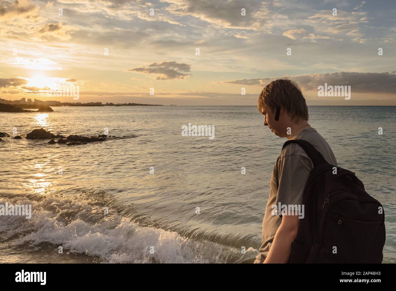 El hombre caucásico con mochila está caminando a lo largo del mar en la  playa de Hamdeok al atardecer Fotografía de stock - Alamy