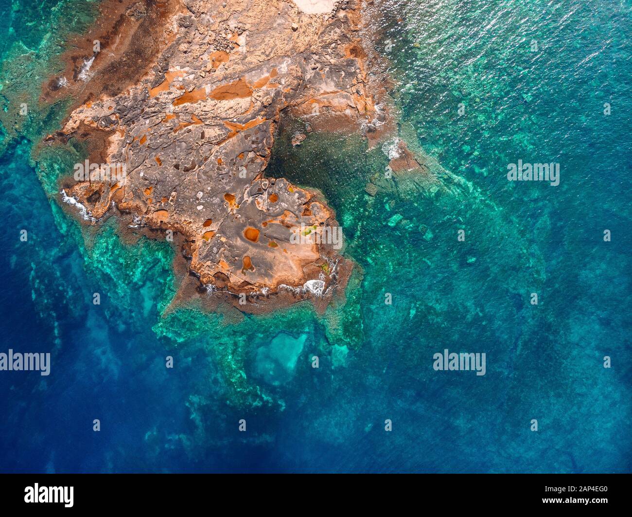 El agua clara de Azure llega a la costa rocosa de la playa de coral. Vista superior aérea Foto de stock
