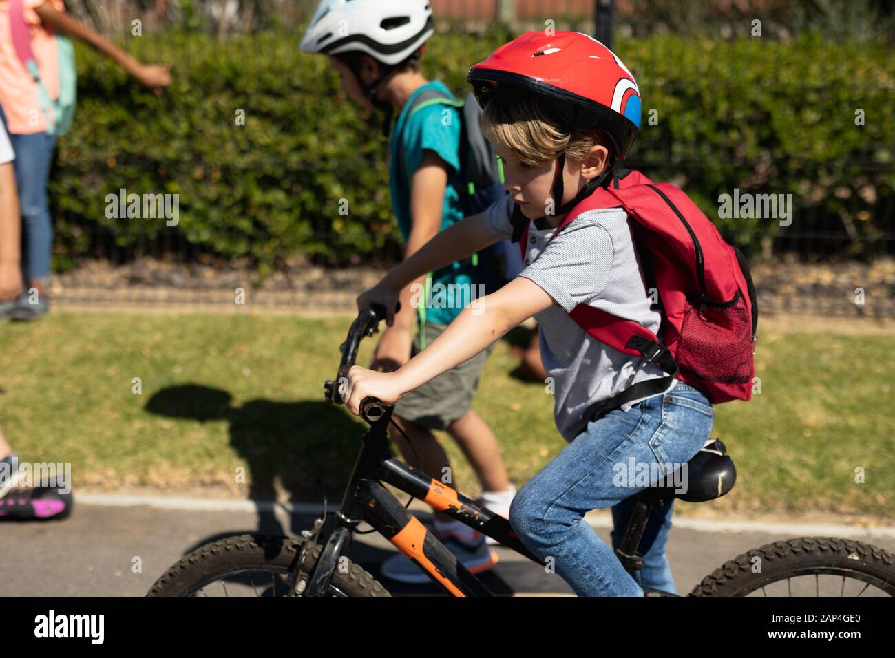 Niño escolar que lleva un casco de ciclismo y que monta en bicicleta Foto de stock