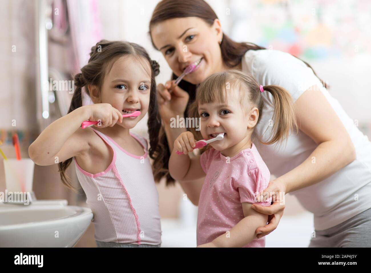 feliz familia mamá y niños cepillando sus dientes Foto de stock