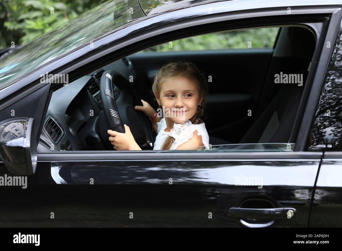 Pericia Magnético Hacer la vida Poco feliz chica sentada detrás del volante del coche de papá Fotografía de  stock - Alamy