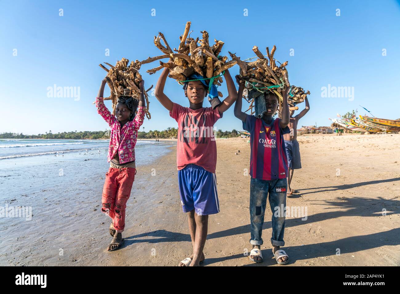 Kinder am Strand tragen Brennholz Bündel auf dem Kopf, Sanyang, Gambia, Westafrika | niños en la playa llevando los manojos de leña sobre sus él Foto de stock