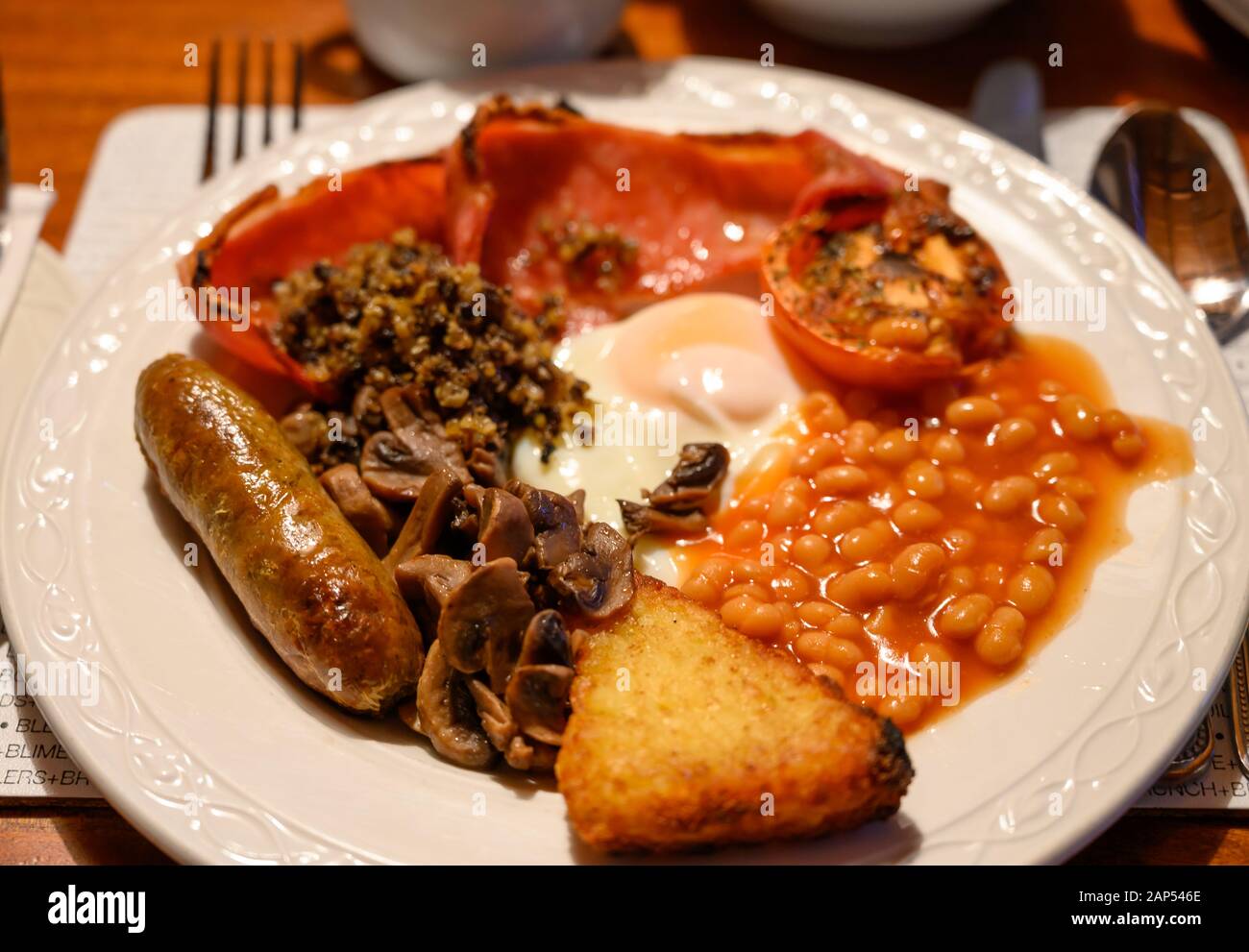 Pizarra blanca con desayuno escocés completo con tocino, huevo frito, frijoles, tomate, salchichas asadas, pudín, croquetas de patata y haggis Foto de stock