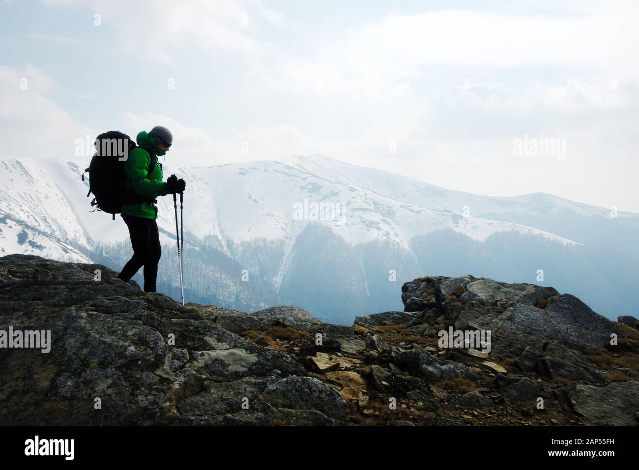 Excursionista con mochila silueta en montañas nevadas de fondo gama Foto de stock