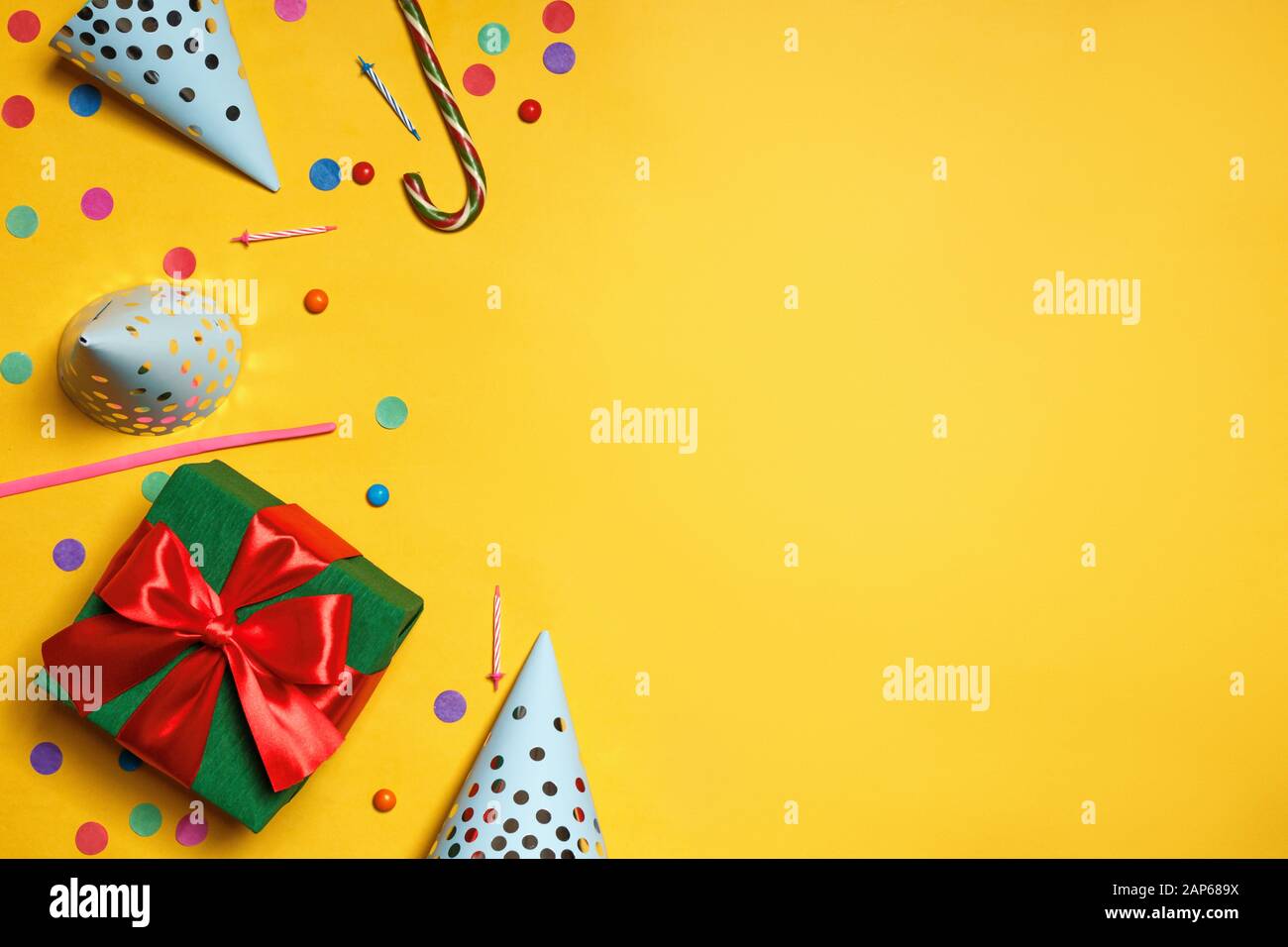 Cumpleaños fondo amarillo con fiesta gorras regalos confetti dulce copia espacio. Foto de stock