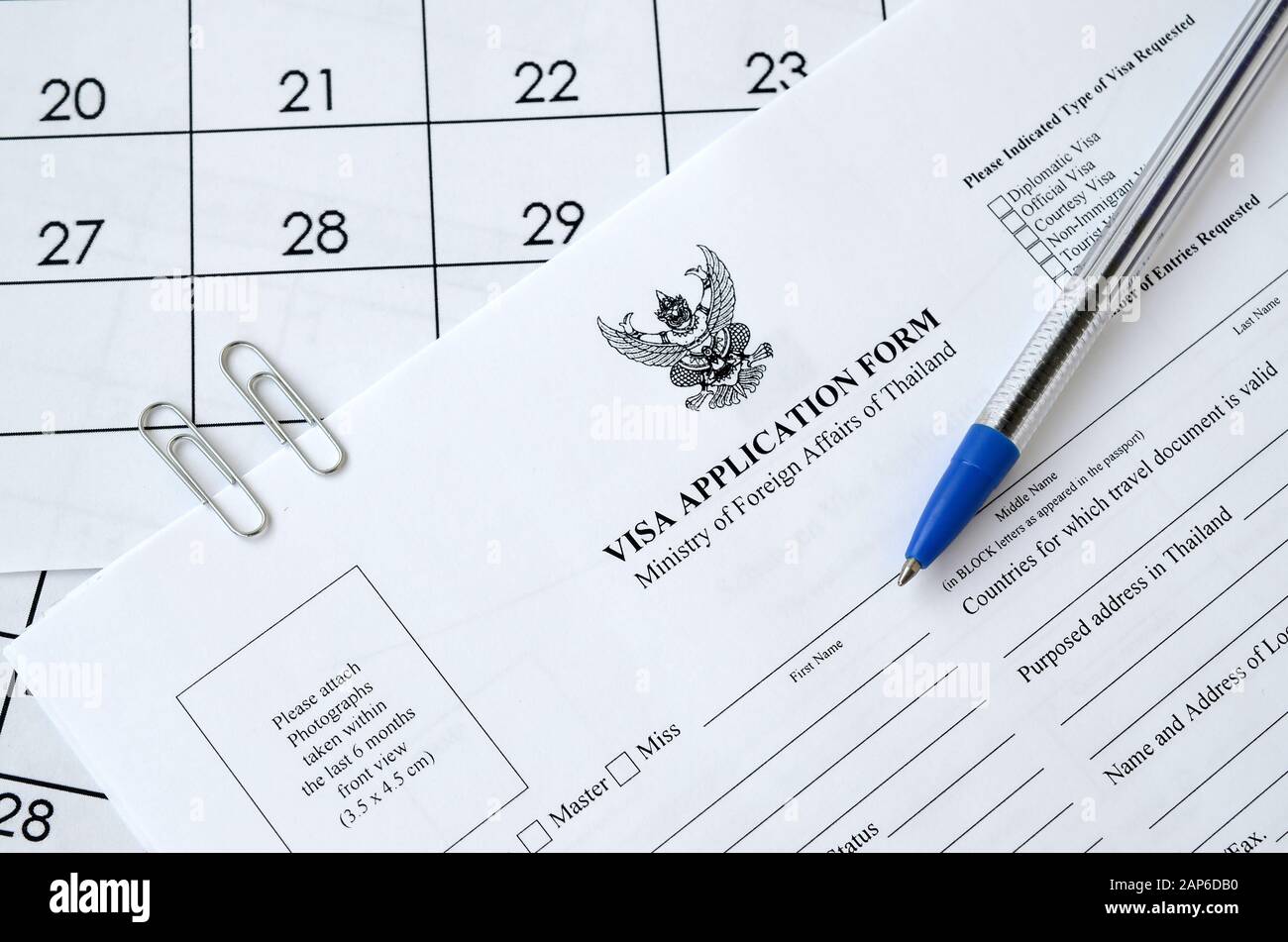 Formulario de solicitud de visado de Tailandia y bolígrafo azul en la página del calendario en papel de cerca Foto de stock