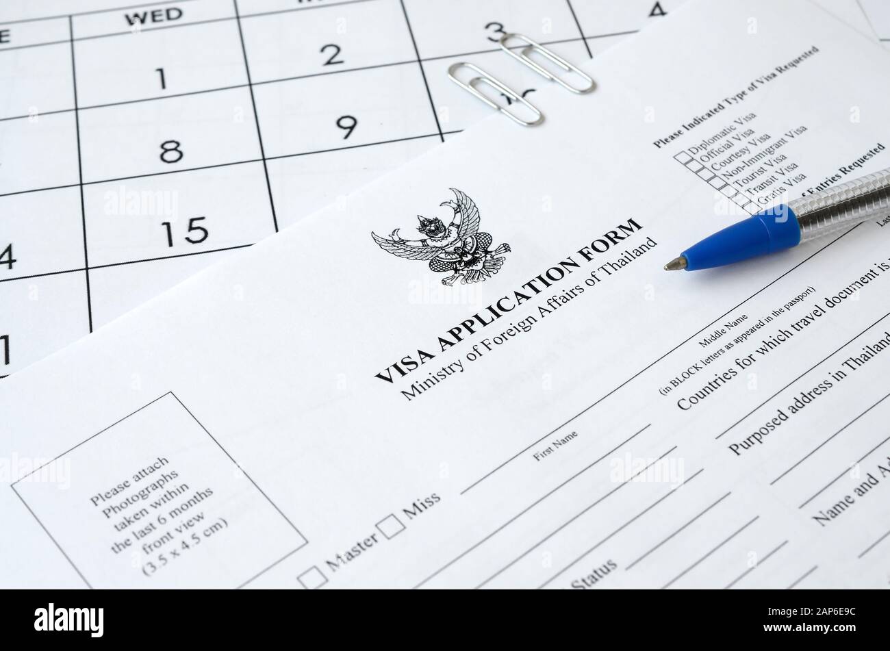 Formulario de solicitud de visado de Tailandia y bolígrafo azul en la página del calendario en papel de cerca Foto de stock