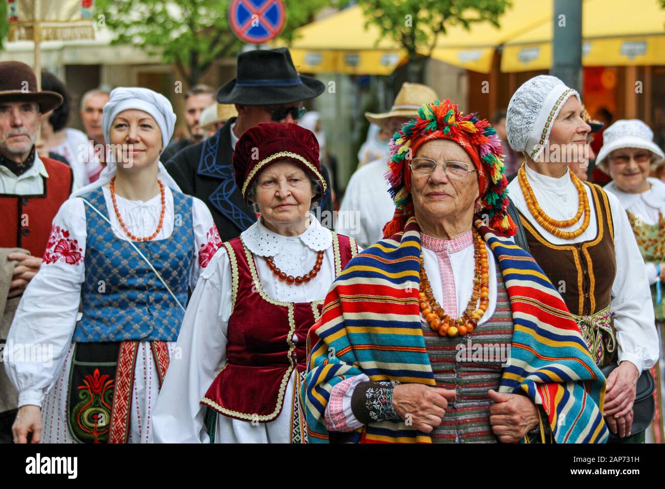 Mujeres mayores y jóvenes con trajes folclóricos que se adan en las calles de Vilna, Lituania Foto de stock