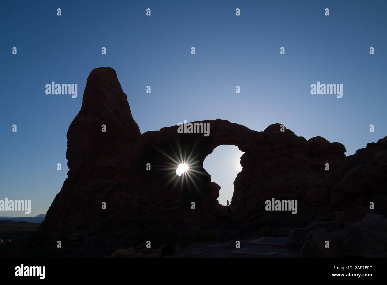 Parque Nacional Arches En Utah. El rayo del sol se muestra a través de las rocas en la formación de Turret Arch mostrando la silueta de un hombre y el arco. Foto de stock