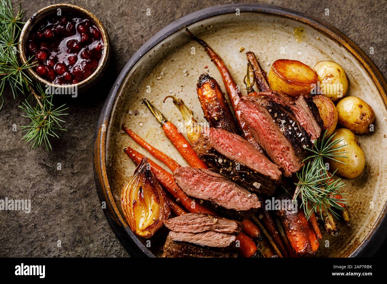 Filete de venado a la parrilla con verduras al horno y salsa de bayas sobre  fondo oscuro Fotografía de stock - Alamy