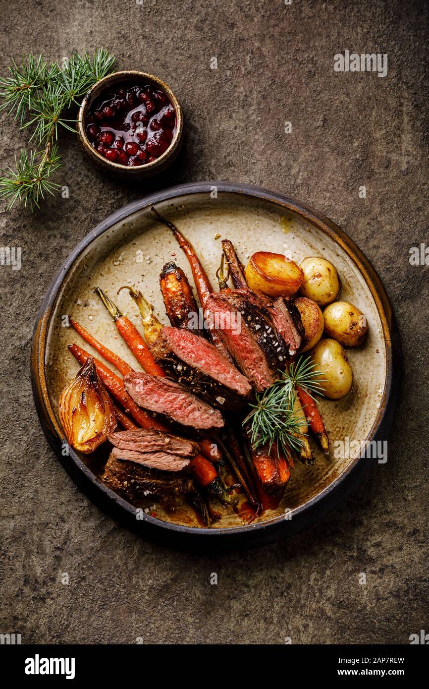 Filete de venado a la parrilla con verduras al horno y salsa de bayas sobre  fondo oscuro Fotografía de stock - Alamy