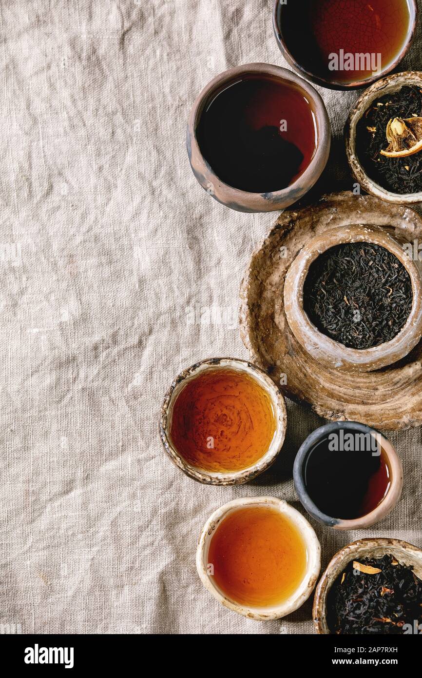 Variedad de té caliente y seco en verde y negro, en estilo tradicional y wabi sabi refractario artesanía cerámica vasos y copas, servidas en tela de lino como backgrou Foto de stock