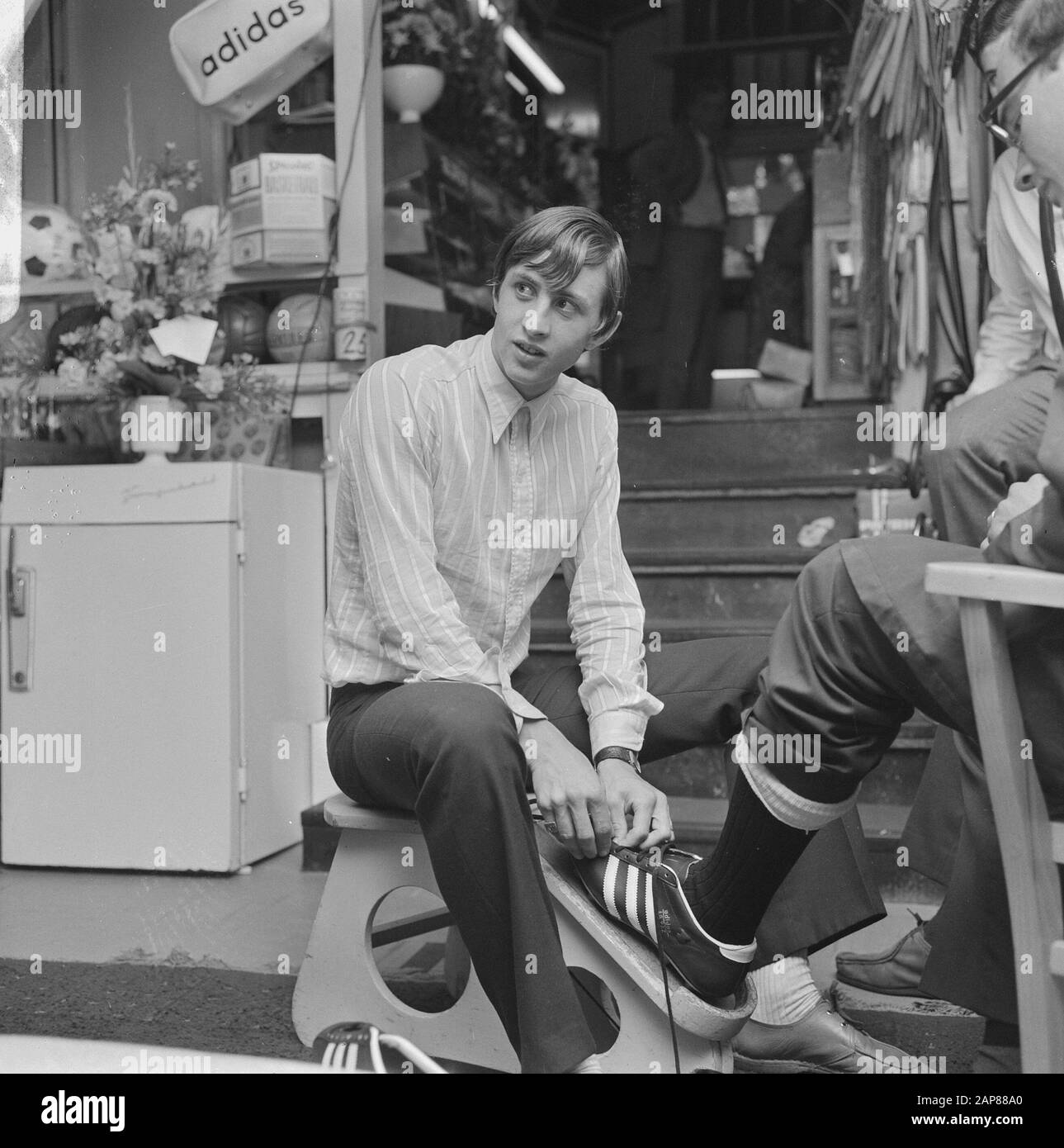 Johan Cruijff en su tienda de deportes Descripción: Cruyff ayuda al cliente  a adaptarse a las zapatillas Fecha: 8 de agosto de 1968 ubicación:  Amsterdam, Noord-Holland palabras clave: Retratos, asuntos deportivos Nombre