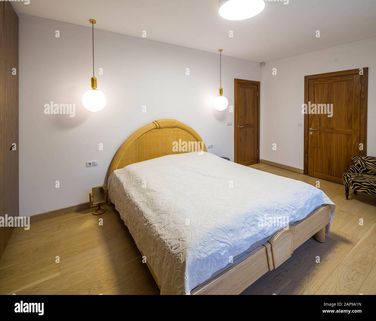 Interior moderno y luminoso del dormitorio. Cama de matrimonio con respaldo  redondo. Lámparas redondas. Puertas de madera Fotografía de stock - Alamy