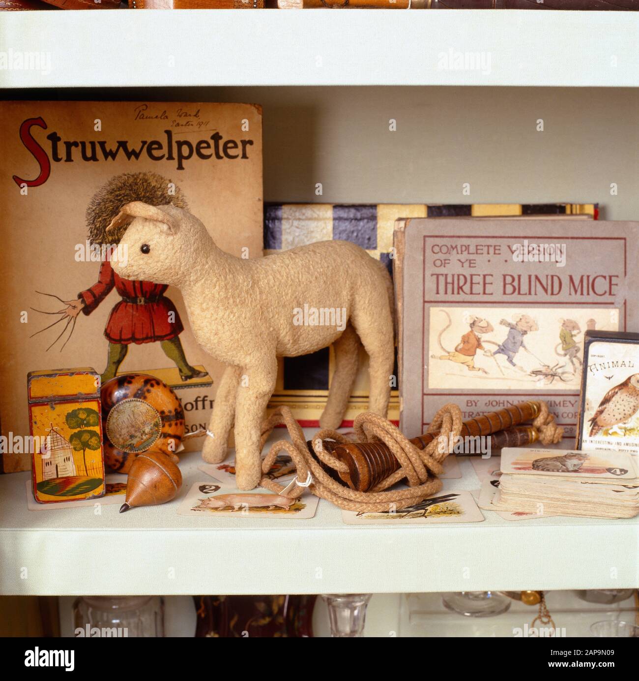 Primer plano de la estantería de juguetes en la colección DE PIEZAS DE Llanerchaeron. Un suave cordero de juguete jostles para el espacio con una cuerda que salta, spinnin Foto de stock