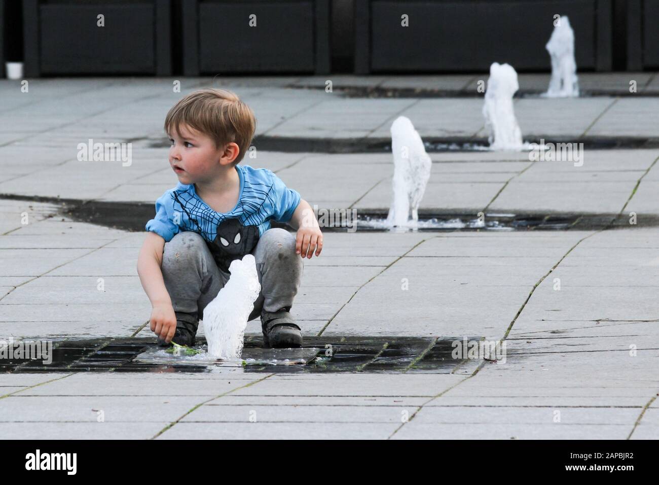 Joven jugando con el chorro de agua en Vilnius, Lituania Foto de stock