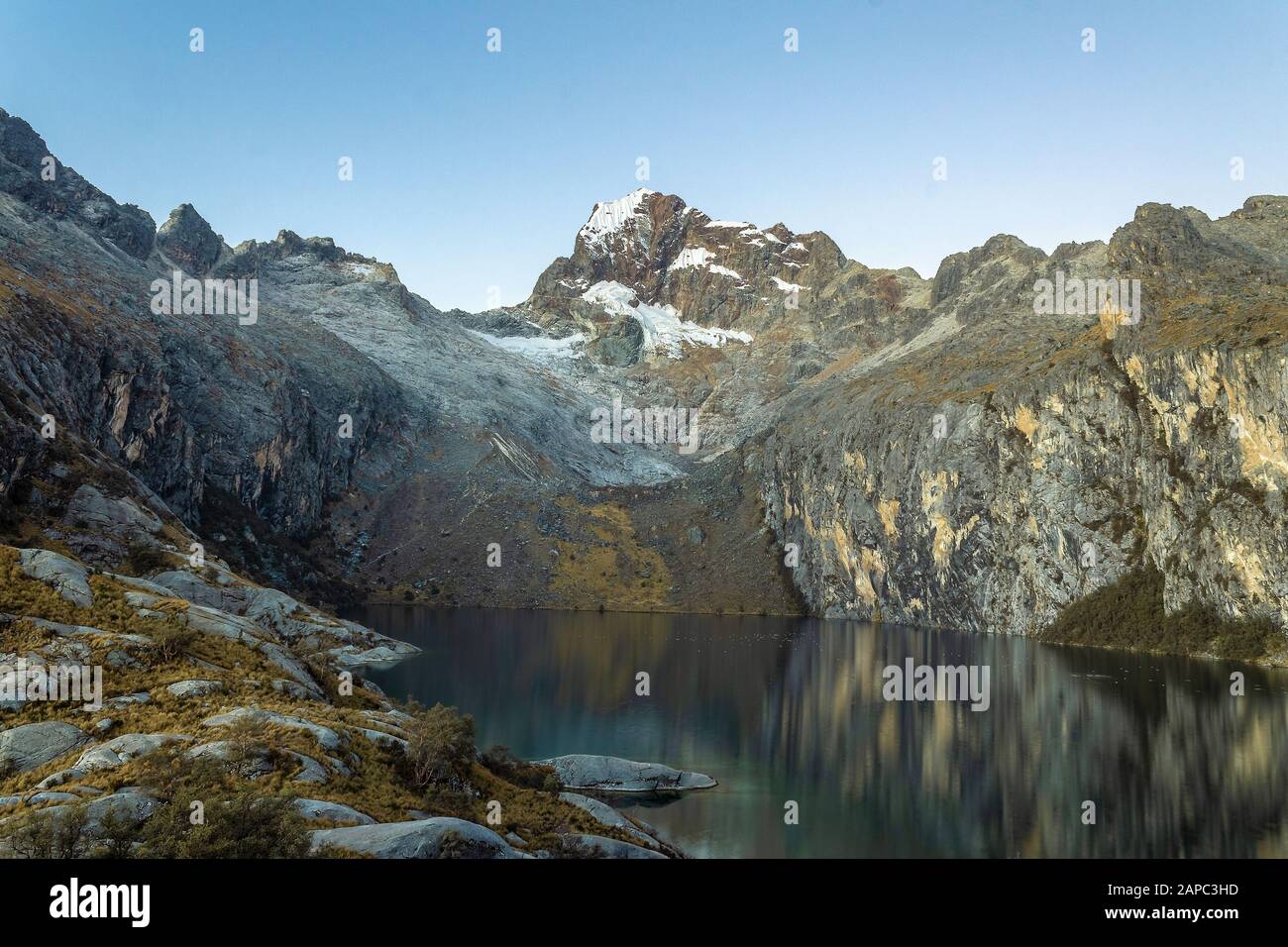 Montaña en Perú con lago, rocas y hierba por la mañana. Foto de stock