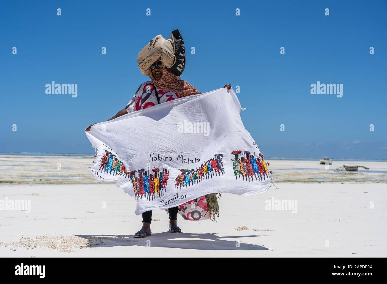 Zanzíbar, Tanzania - 28 de octubre de 2019 : una mujer africana vende ropa para turistas cerca del océano en la playa de arena de la isla de Zanzíbar, Tanz
