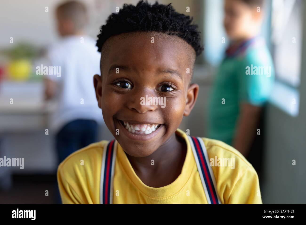 El chico escolar que busca cámara en un salón de clase de la escuela primaria en un salón de clase de la escuela primaria Foto de stock
