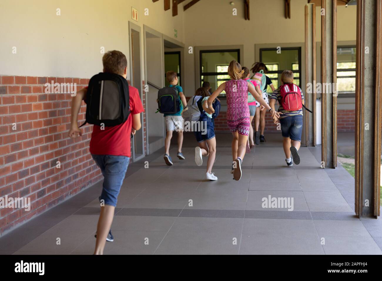 Grupo de escolares que corren en un corredor al aire libre en la escuela primaria Foto de stock