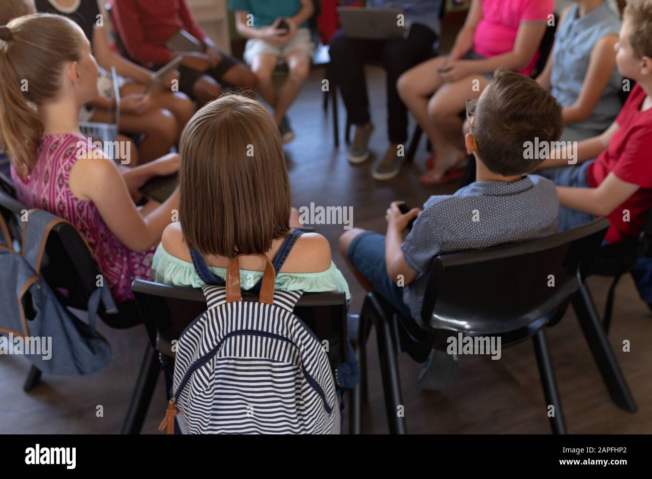 grupo de escolares sentados en una silla en un círculo en un salón de clases de escuela primaria Foto de stock