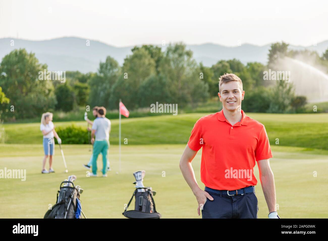 Hombre con amigos jugando al golf en el campo de golf en el fondo Foto de stock