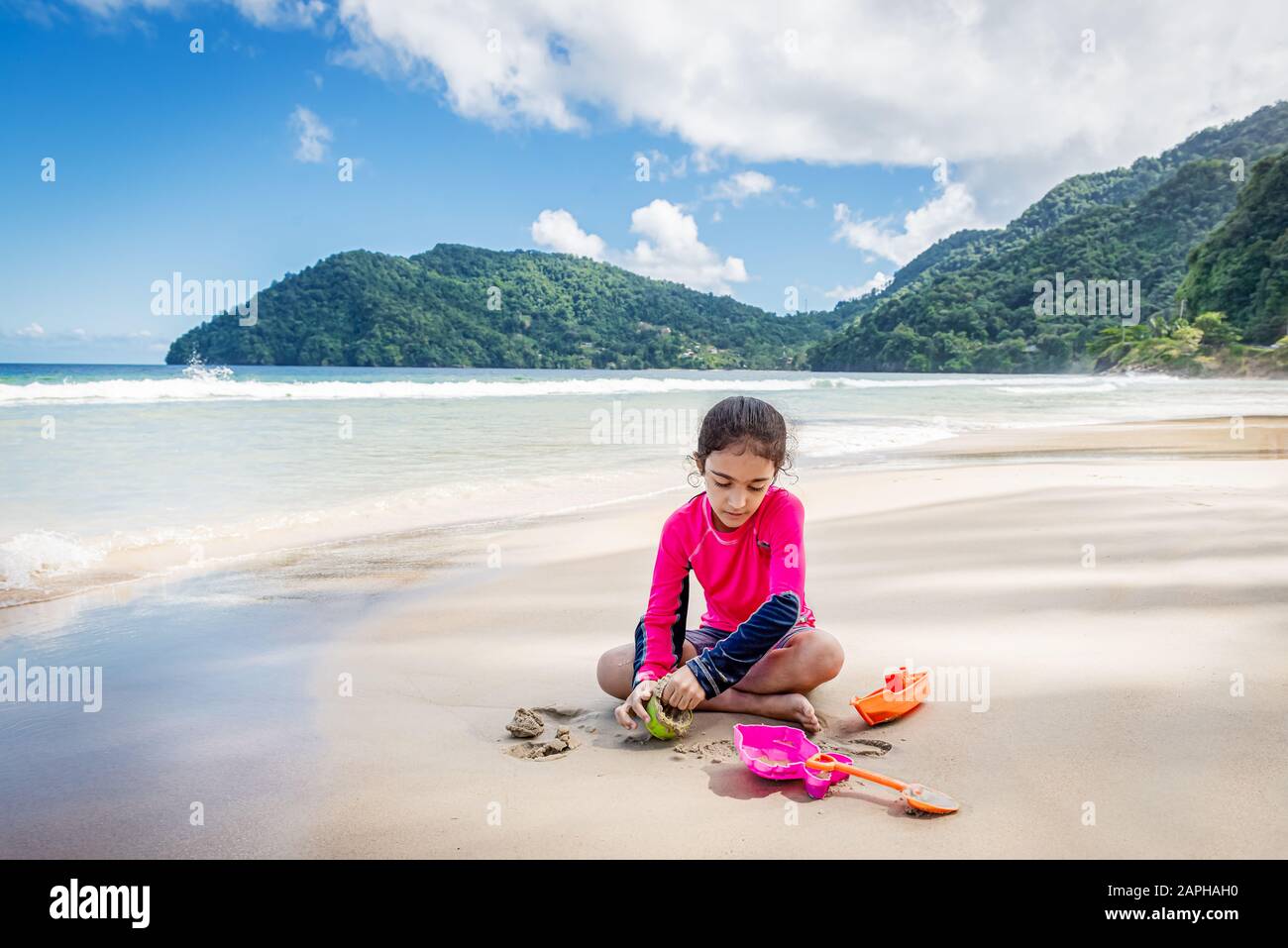 Niña jugando con arena en las Maracas Bay Beach Trinidad y Tobago sentados al aire libre actividad divertida Foto de stock