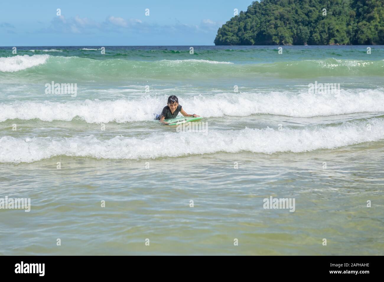 Niño mayor nadando en Maracas Bay Beach Trinidad y Tobago pasándose por las olas mirando Foto de stock