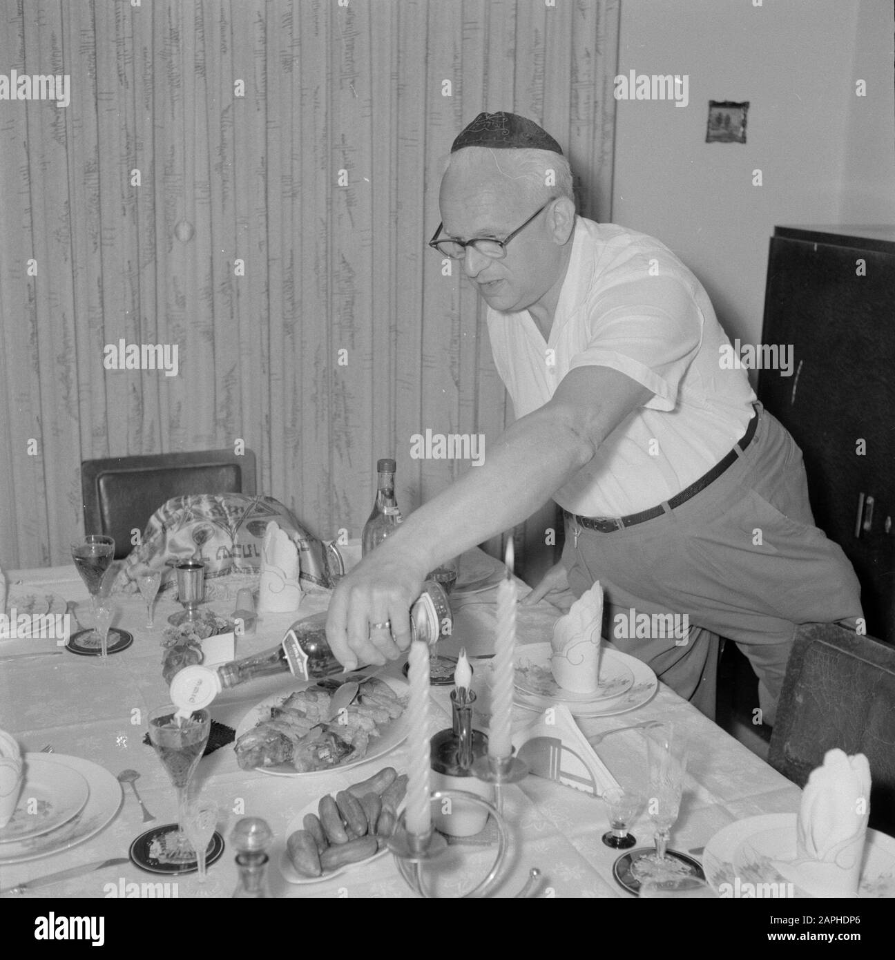 Comida el viernes por la noche, en la víspera del Shabbat Descripción: El  Señor de la Casa vierte vino en vasos para la comida del sábado Fecha: 1 de  enero de 1963