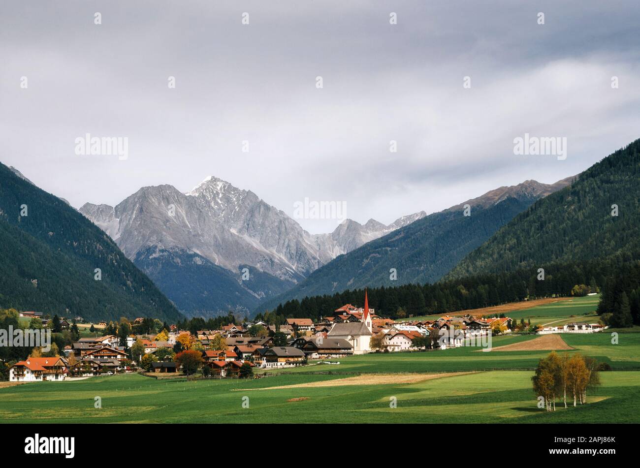 Vista del pueblo alpino de montaña y prados verdes en los Alpes Dolomitas italianos, Trentino Alto Adige, Italia en otoño Foto de stock