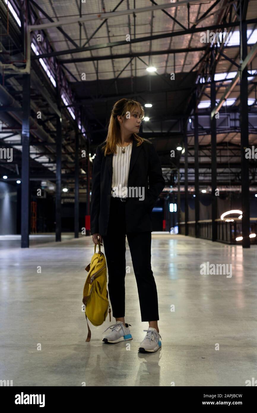 Mujer rubia en la ropa semi-formal de pie con postura fresca en el edificio sosteniendo la mochila amarilla después de la visita del cliente de stock - Alamy