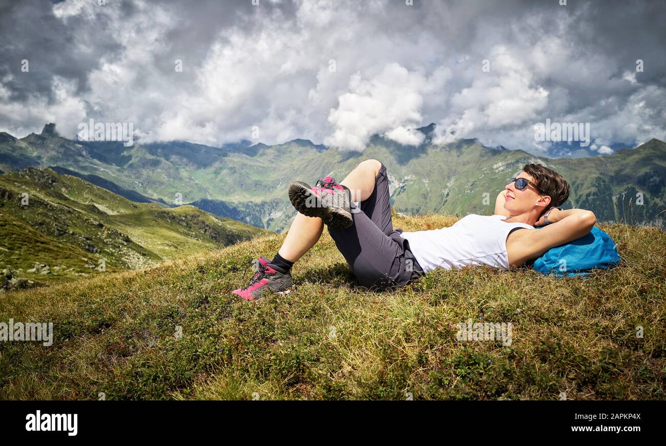 Mujer que tiene un descanso de senderismo en la pradera alpina, Passeier Valley, Tirol del Sur, Italia Foto de stock