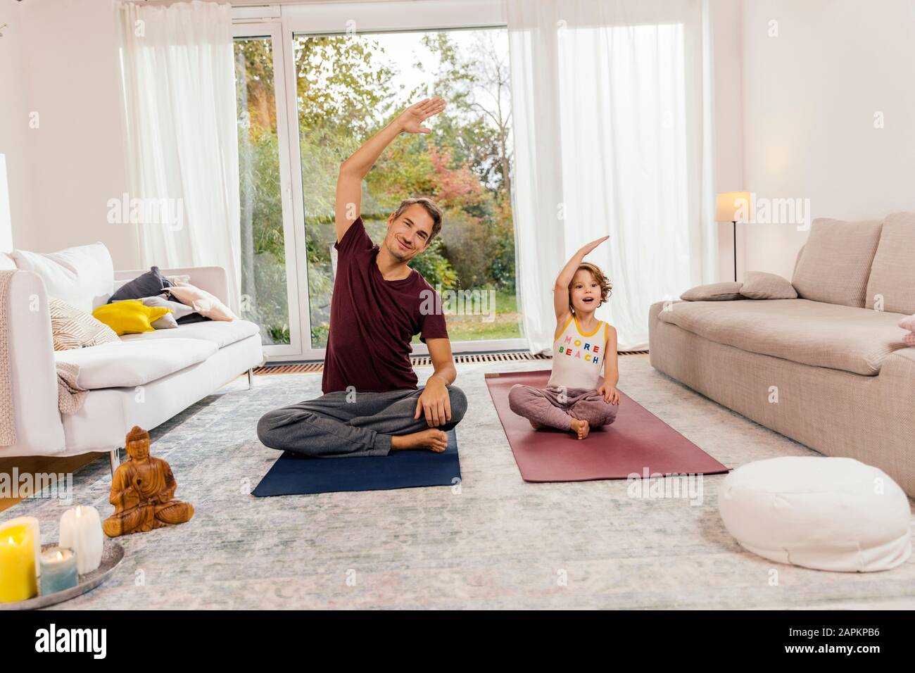 Padre e hija haciendo yoga juntos en casa Foto de stock