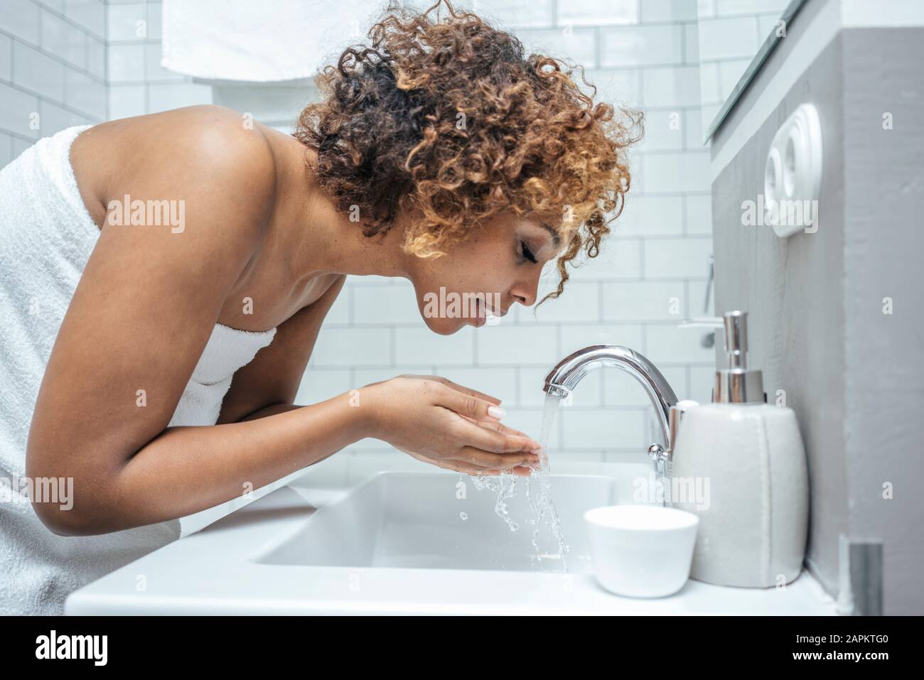 Mujer joven en el lavabo del baño Foto de stock